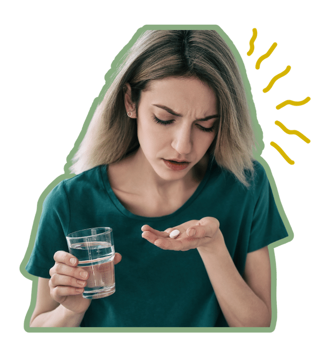 A woman with a stressed look on her face holding a pill and a glass of water