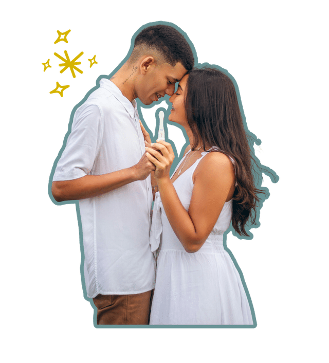 A young man and woman turned towards one another with their heads touching and smiles on their faces while holding a pregnancy test togethter