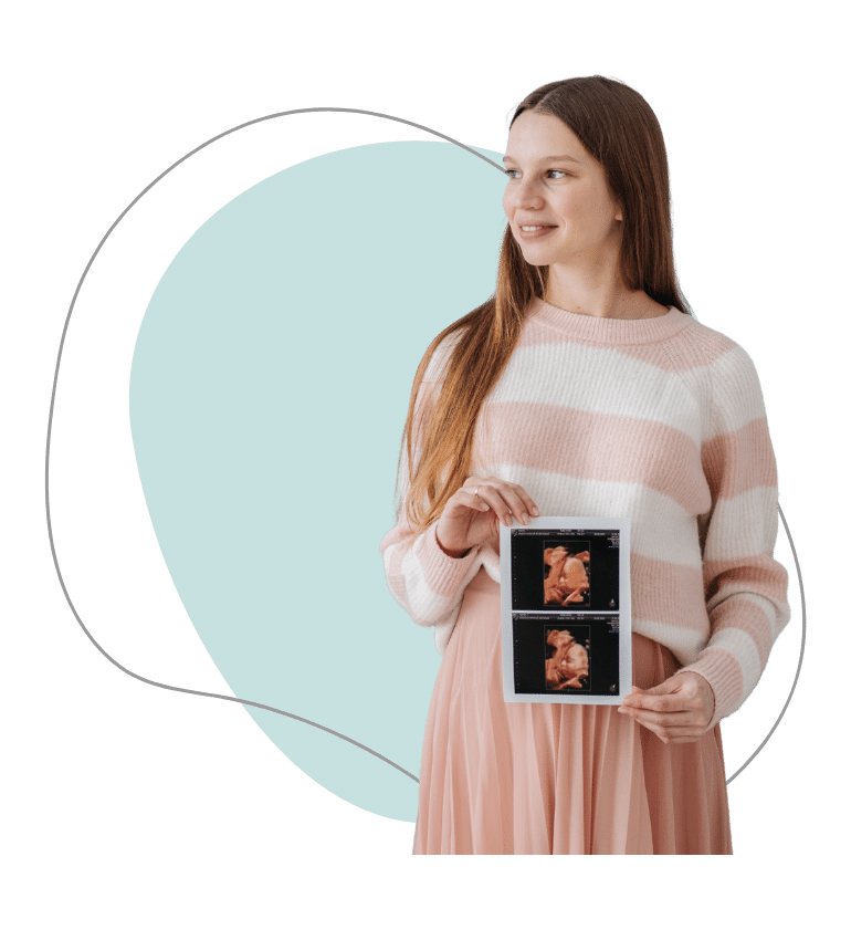 A woman in pink clothing holding ultrasound images